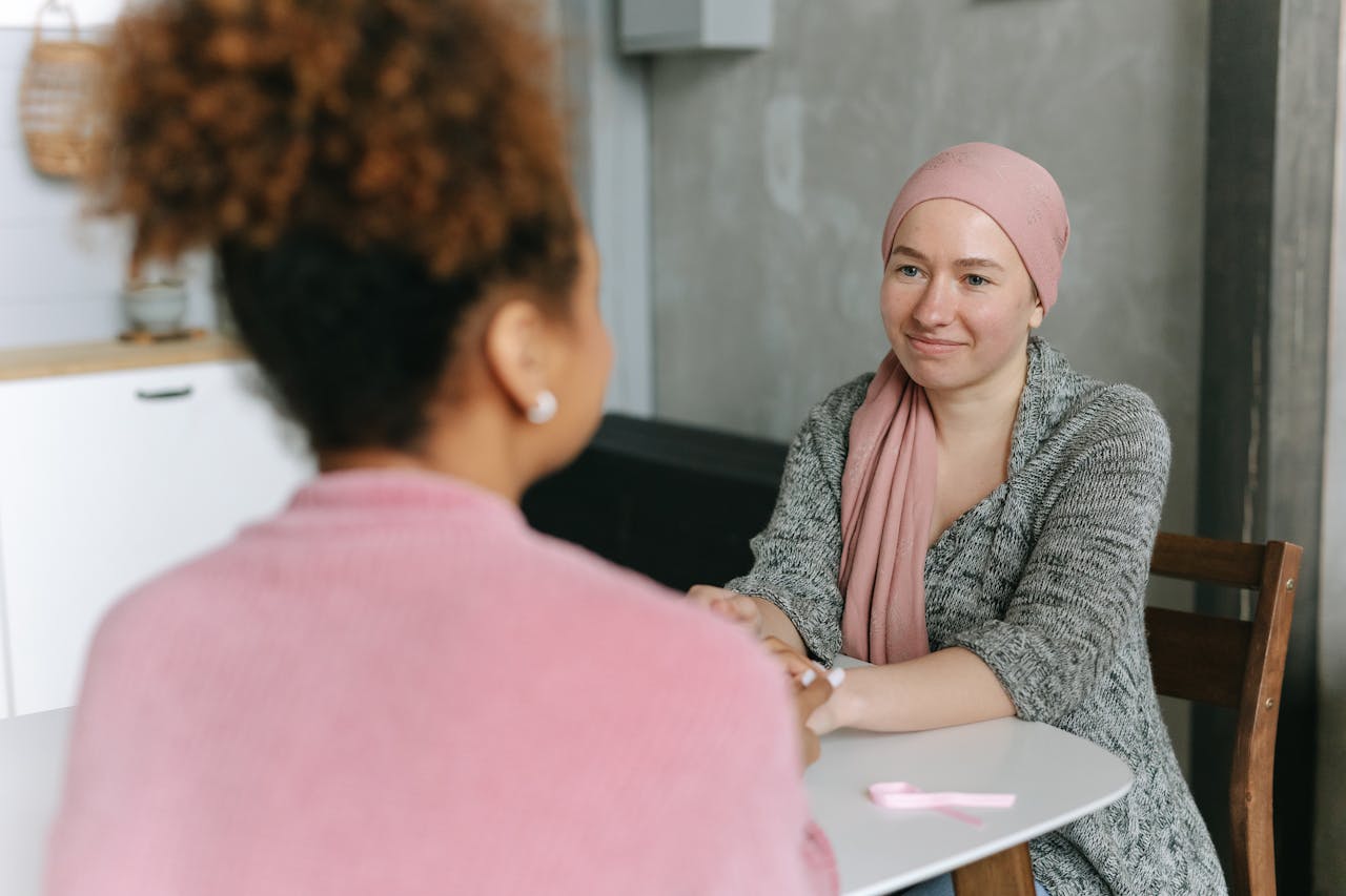 Two women sharing a supportive moment, symbolizing cancer awareness indoors.